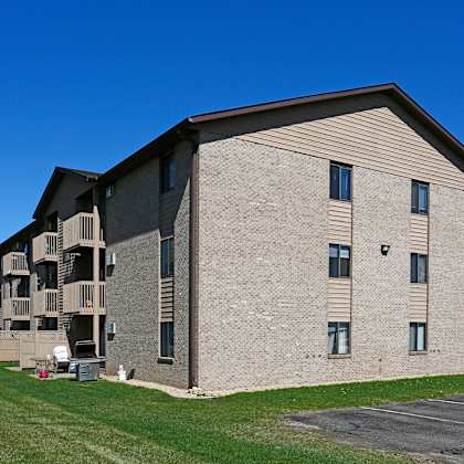 a large apartment building with a parking lot in front.