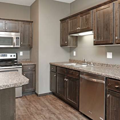a kitchen with wooden cabinets and granite counter tops and stainless steel appliances
