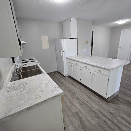 a kitchen with a white counter top and a white refrigerator.
