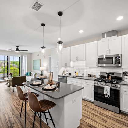 a modern kitchen with white cabinets and a wooden floor.