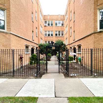 a courtyard between two brick buildings with a wrought iron gate
