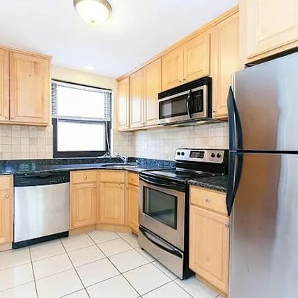 a kitchen with wooden cabinets and black countertops.