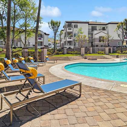 community swimming pool with pool furniture at reserve at rancho apartments located in moreno valley, ca.