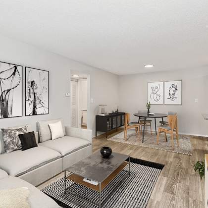 model living room with wood-style flooring and view of kitchen/dining area at seven lakes at carrollwood apartments in tampa, fl.