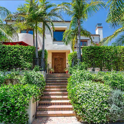 a house with stairs and a door in the middle of a garden