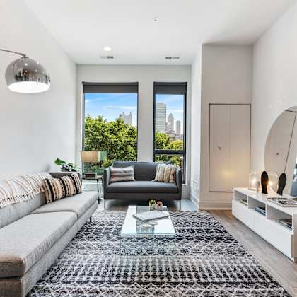 a modern living room with a cozy  grey couch, modern floor lamp, and large windows
