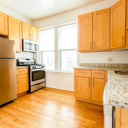 an empty kitchen with wood floors and wooden cabinets