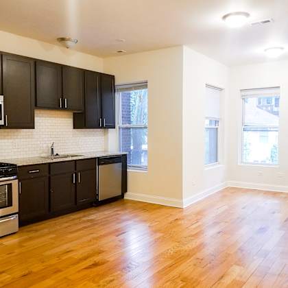 an empty kitchen with black cabinets and a wood floor