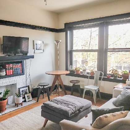 a living room with a grey sofa, a white chair, a wooden table, and a television on a black stand.