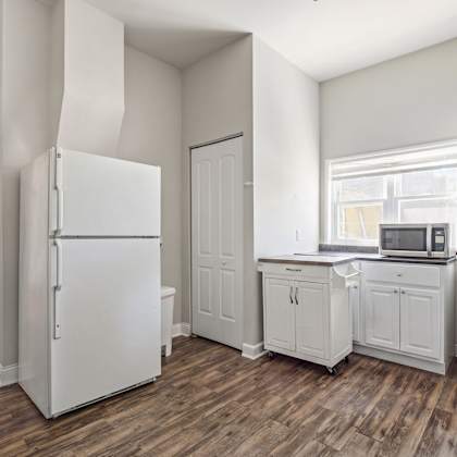 a white kitchen with wood floors and white appliances.