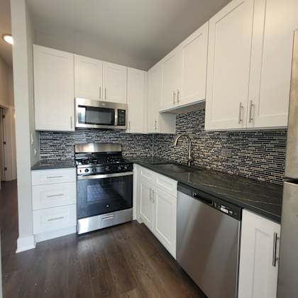 a kitchen with white cabinets and stainless steel appliances