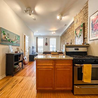 a kitchen with a stove top oven and a wooden floor.