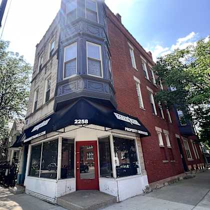 a building on the corner of a street with a red door and a black awning