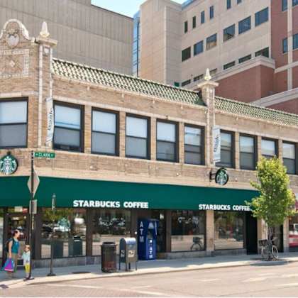 a starbucks coffee shop is located in a building with a green awning.