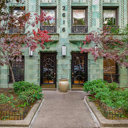 a green building with a black gate and a large door.