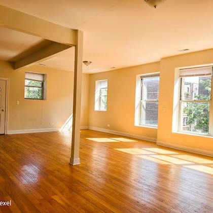 an empty living room with a hard wood floor and large windows