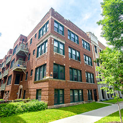 a red brick building with green grass and trees