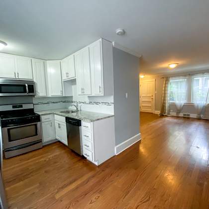 an empty kitchen with white cabinets and stainless steel appliances