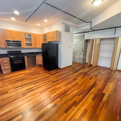 a kitchen with wooden floors and a black refrigerator.