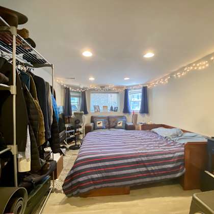 a bedroom with a bed, a clothing rack, and a window with curtains.