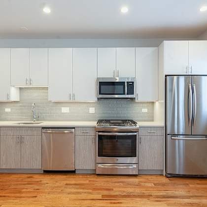 a modern kitchen with wooden floors and stainless steel appliances.