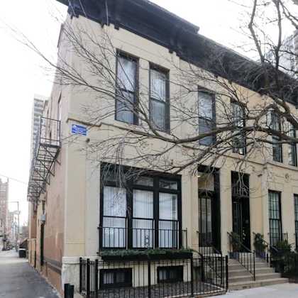 a beige building with black railings and a black awning.