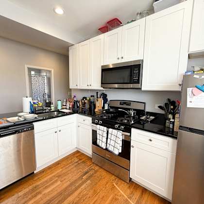 a kitchen with white cabinets and black countertops.