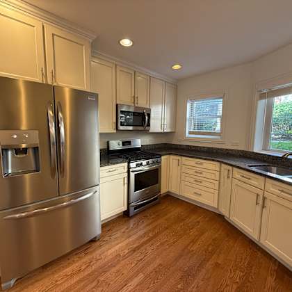 a kitchen with a stainless steel refrigerator and wooden floors.
