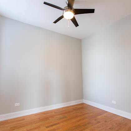 a room with a ceiling fan and wooden floors.