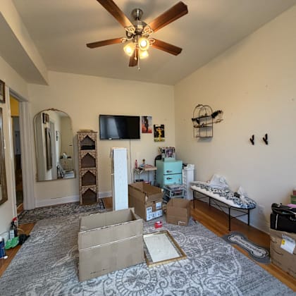 a room with a ceiling fan and boxes on the floor.