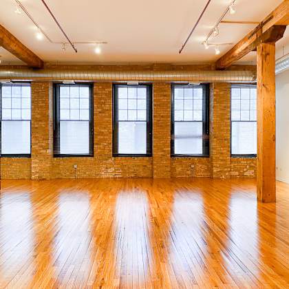 a large empty room with wooden floors and brick walls.