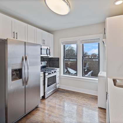 a kitchen with white cabinets and a stainless steel refrigerator.
