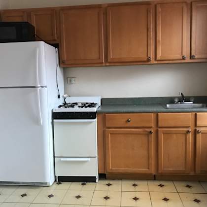 a kitchen with a white fridge, black microwave, and a white stove.
