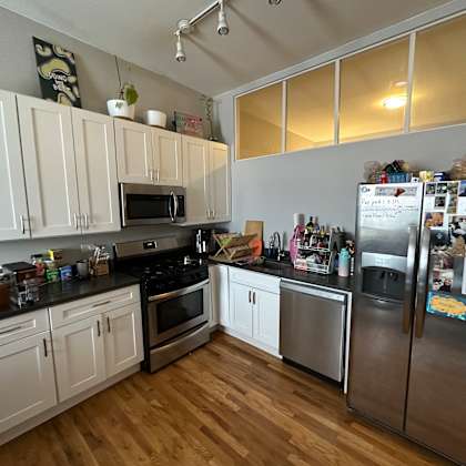 a kitchen with white cabinets and a fridge filled with magnets.