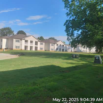 a building complex is located in a grassy area with trees.