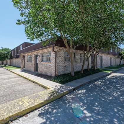 a parking lot with a building and a tree in front.