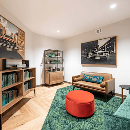 a living room with a green couch and a red ottoman.