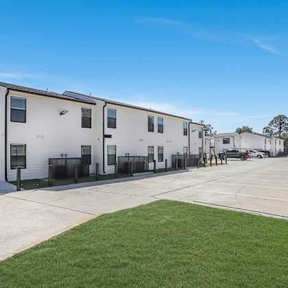 a row of white houses with a green lawn in front.