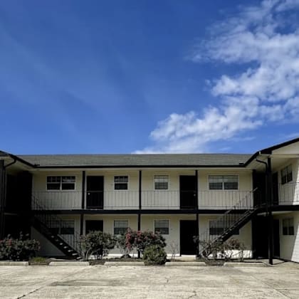 a white two-story building with a flat roof and a balcony on the second floor.