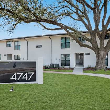 a sign with the number 4747 is in front of a building with a tree.