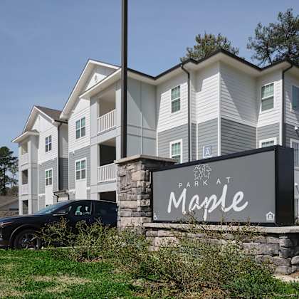 a large building with a sign that says "park at maple".