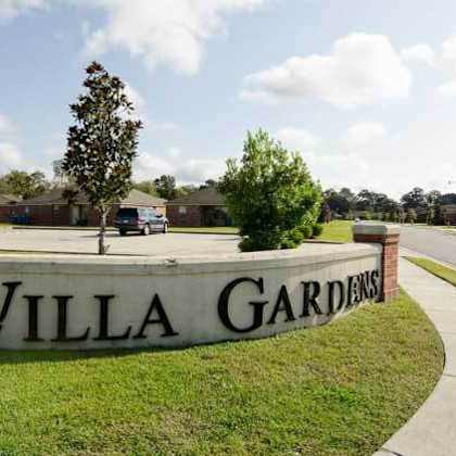a sign that says "villa gardens" in front of a grassy area.