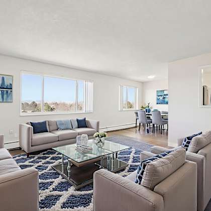 a living room with a glass coffee table and two couches.