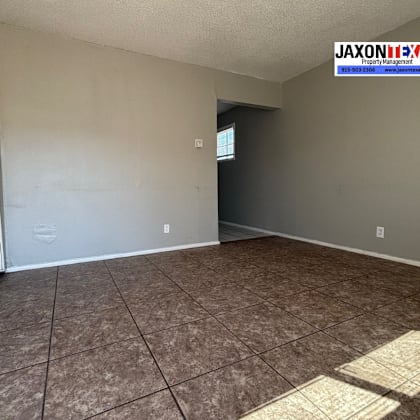 a room with a tiled floor and a window with a closed shutter.