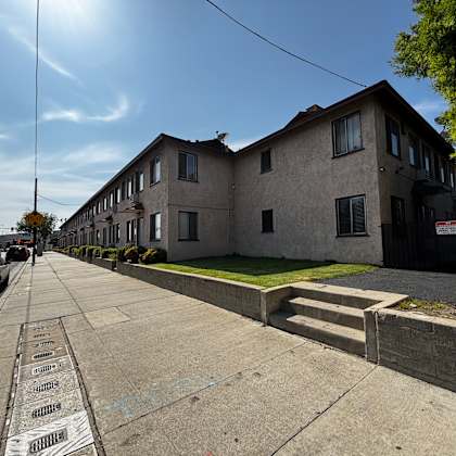 a sunny day in a residential area with houses on one side and a sidewalk with a series of names on it.