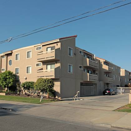 a beige apartment building with a car parked in front.