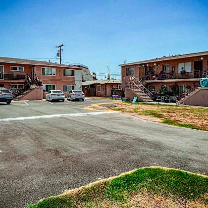 a parking lot in front of apartment buildings with cars parked.