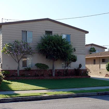 a house with a green lawn and a white car parked in front.