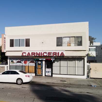 a white car is parked in front of a carnicería.