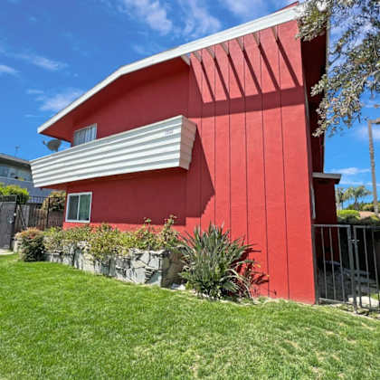 a red house with a white roof and a green lawn in front.